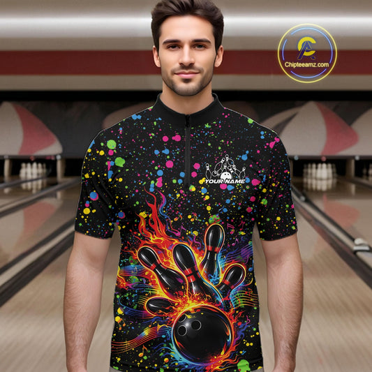 Male model wearing a black bowling quarter-zip shirt at the lane with vibrant music-themed splatters and bowling strike artwork.