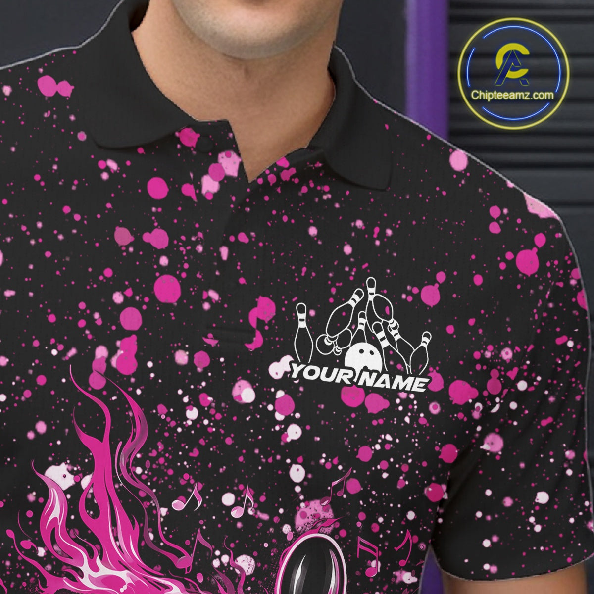 Close-up of the left chest on a black bowling polo shirt featuring flaming bowling pins and pink splatter graphics.