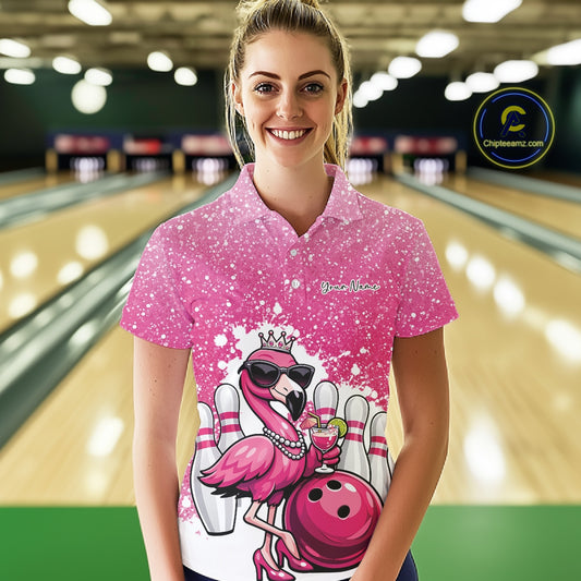 Female model wearing a pink bowling polo shirt at a bowling lane with a crowned flamingo, cocktail, bowling ball, and paint splatter graphics.