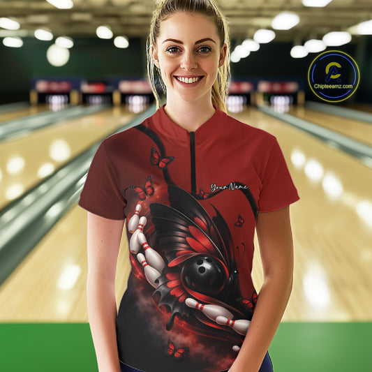 Female model wearing a red and black bowling quarter-zip shirt at the bowling lane with butterfly artwork, bowling ball, and pin accents.