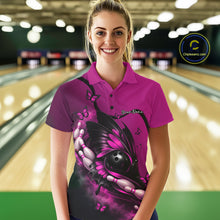 Load image into Gallery viewer, Female model at a bowling lane wearing a pink and black bowling polo shirt with butterfly artwork embracing a bowling ball and pins.