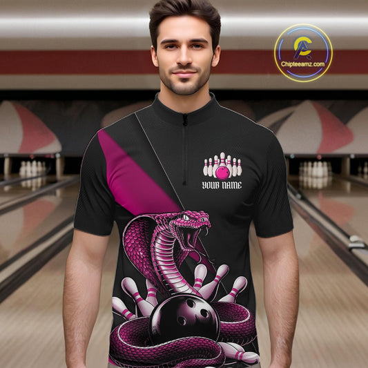 Male model at a bowling alley wearing a black quarter-zip with pink cobra artwork wrapped around a bowling ball.