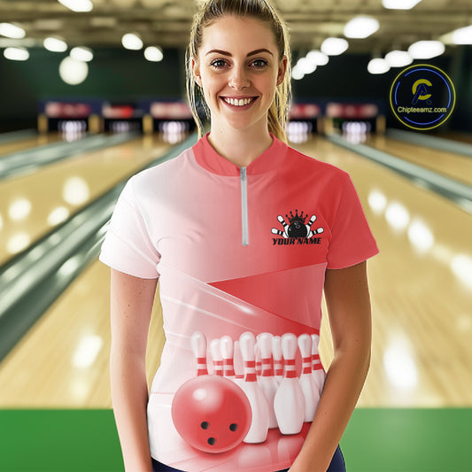 Front view of a female model at the bowling lane wearing a quarter zip shirt with bowling ball and pins arranged in a pink gradient layout.