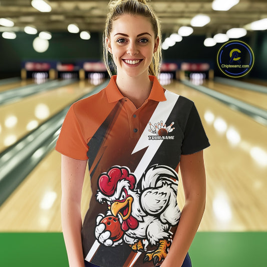 A woman stands in a bowling alley wearing a custom-designed polo shirt with a bold graphic print featuring cartoon chickens and a white lightning bolt. The shirt has orange sleeves, a black right side, and a white center stripe.