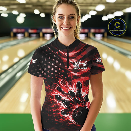 Female model in a black bowling quarter-zip shirt at the bowling lane with red flame bowling strike graphics and flag-inspired accents.