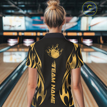 Load image into Gallery viewer, Female model back view in a bowling lane wearing a black polo shirt featuring a golden metal tribal flame design with a bowling ball striking pins in vivid motion.