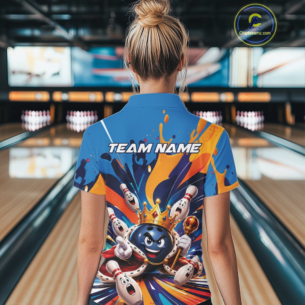 Back view of a female model wearing a bowling quarter zip shirt featuring a crowned cartoon bowling ball holding a royal scepter with animated bowling pins and colorful paint splashes in a bowling lane.