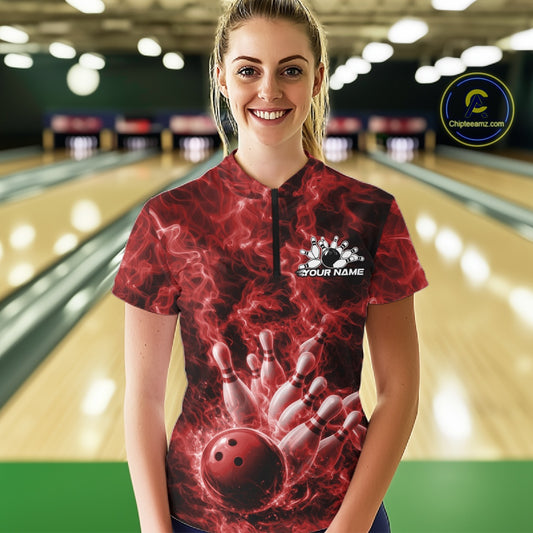 Female model in a bowling lane wearing a quarter-zip decorated with a red bowling ball and fiery bowling strike artwork.