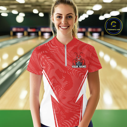 Front view of a happy female model in a bowling alley wearing a red custom quarter-zip bowling shirt with a funny aggressive crawfish holding a bowling ball in a sportswear-style design.