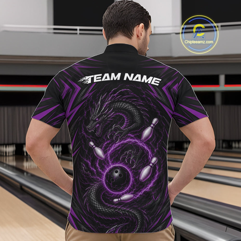 A man viewed from behind wearing a black short-sleeve quarter zip bowling-themed shirt with a purple dragon and bowling pins graphic on the back, standing in a bowling alley. The shirt has 'TEAM NAME' printed in white across the upper back.