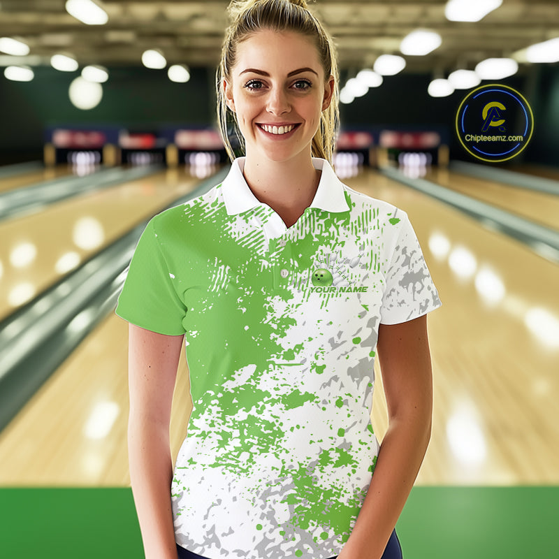 Female model front view in bowling lane wearing white polo shirt with green and white splatter pattern, sporty casual bowling venue scene