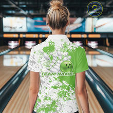 Load image into Gallery viewer, Back view female model at bowling lane wearing white polo with green and white splatter background, relaxed stance inside bowling center