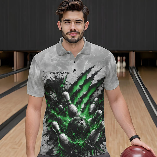 Front view of a male model wearing a gray bowling polo shirt with a dramatic green bowling ball striking pins graphic accented by claw-mark artwork in a bowling lane.