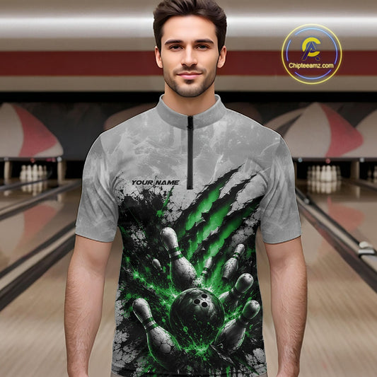 Front view of a male model wearing a gray bowling quarter zip shirt showcasing a dramatic green bowling ball and pins graphic with claw-mark artwork in a bowling lane.