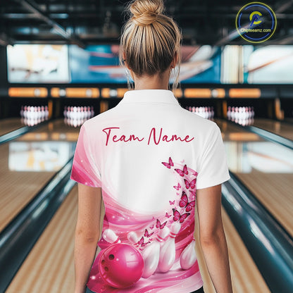 Female model wearing a white and pink bowling polo with butterfly artwork and bowling graphics, back view inside a bowling center