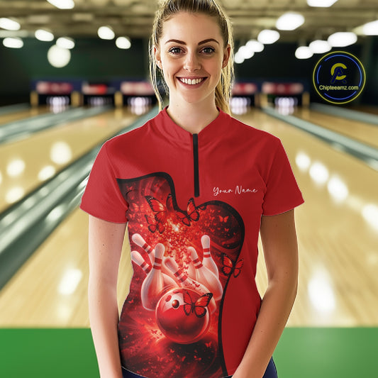 Person wearing a red bowling shirt with a heart design in a bowling alley.