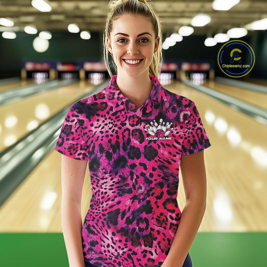 Smiling woman in a bowling alley wearing a gold, brown, and black leopard-print bowling polo with a small bowling pins graphic and “Your Name” on the chest.
