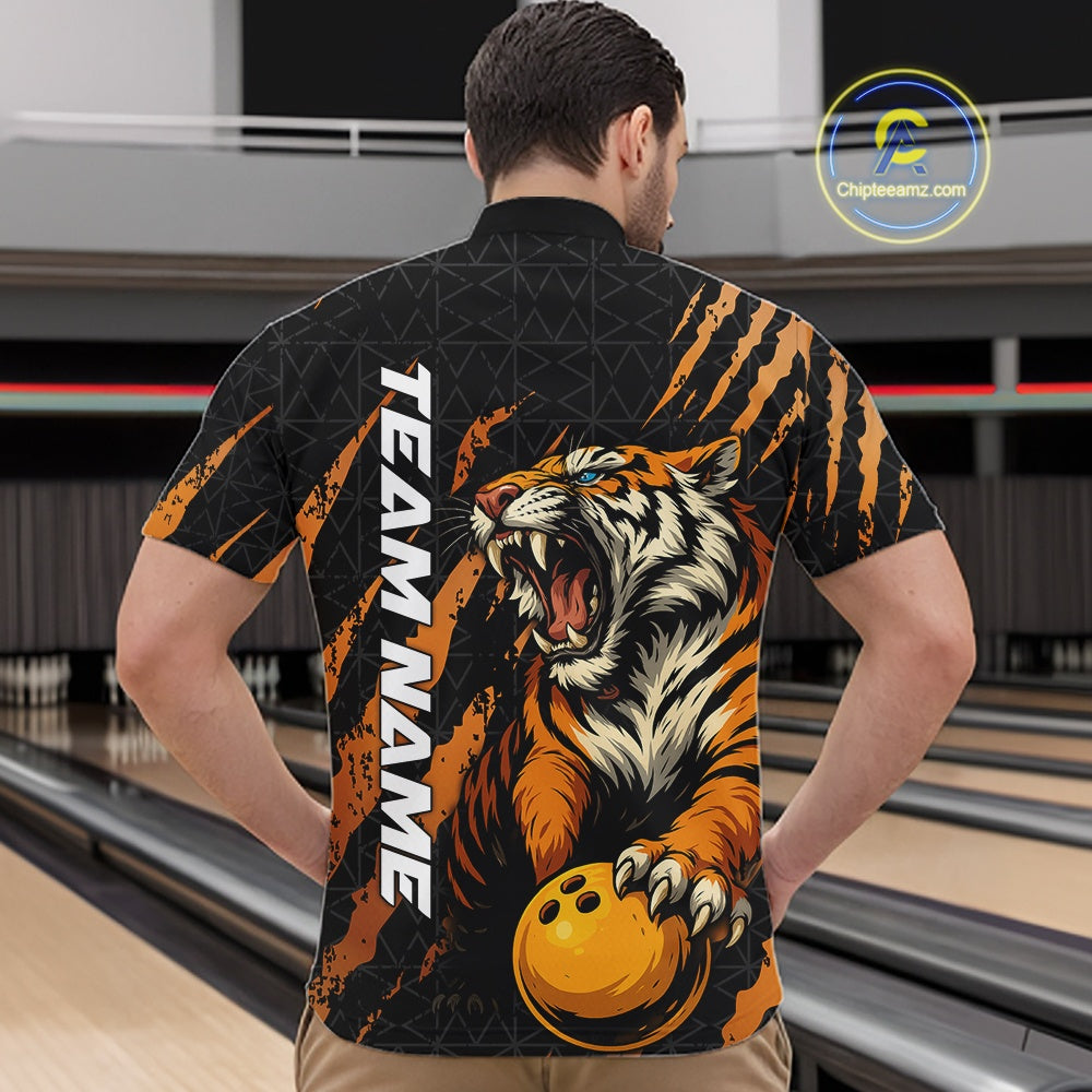 Front view of a male model at a bowling lane wearing a black and yellow bowling quarter-zip shirt featuring a roaring tiger holding a yellow bowling ball with orange claw-stripe artwork and a geometric background pattern.