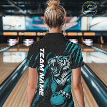 Load image into Gallery viewer, Back view of a female model wearing a black and teal blue bowling quarter-zip shirt at a bowling lane, featuring a roaring tiger holding a teal blue bowling ball with teal blue claw-stripe artwork and a geometric background pattern.
