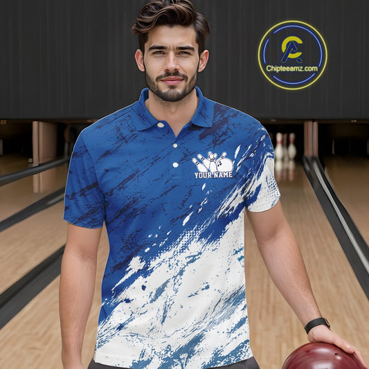 Front view of a male bowler in a bowling alley wearing a white and blue bowling polo shirt with a dynamic splatter style sports jersey design