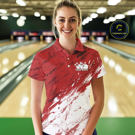 Woman wearing a red and white bowling shirt with a logo in a bowling alley.