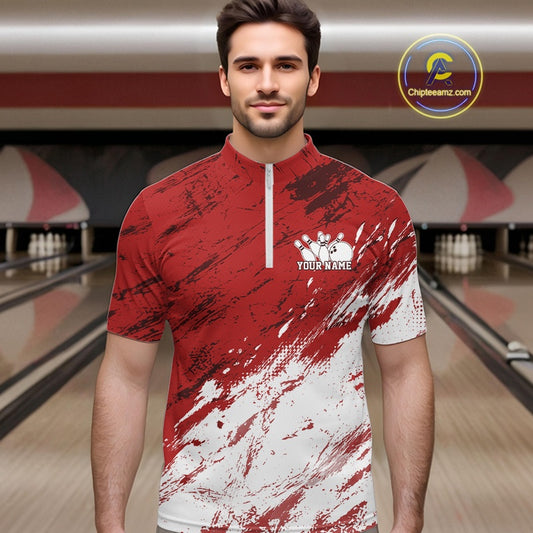 Front view of a male model in a bowling alley wearing a bowling quarter zip shirt featuring a white and red paint splatter distressed sportswear design.
