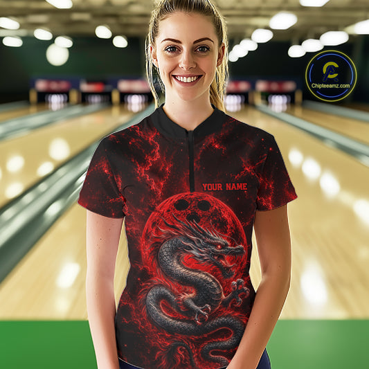 Front view of a happy female model in a bowling alley wearing a red custom quarter-zip bowling shirt featuring an ancient dragon, flames, and a moon-inspired bowling ball design.