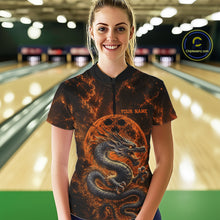 Load image into Gallery viewer, Front view of a happy female model in a bowling alley wearing an orange custom quarter-zip bowling shirt featuring an ancient dragon, flames, and a moon-inspired bowling ball design.