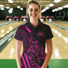 Load image into Gallery viewer, Female model wearing a black bowling polo shirt at a bowling lane with pink flame bowling strike artwork and patriotic styling.