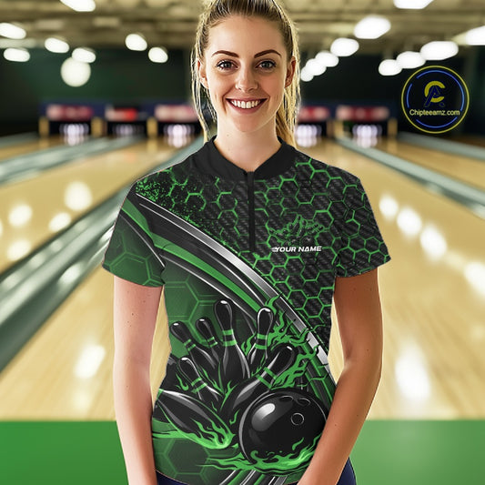 Front view of a female model in a black and green bowling quarter zip featuring honeycomb graphics and a flaming bowling ball striking pins at the bowling lane.