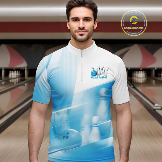 Male model front view in a bowling lane wearing a white and blue bowling quarter zip shirt with bowling ball and pins motif.