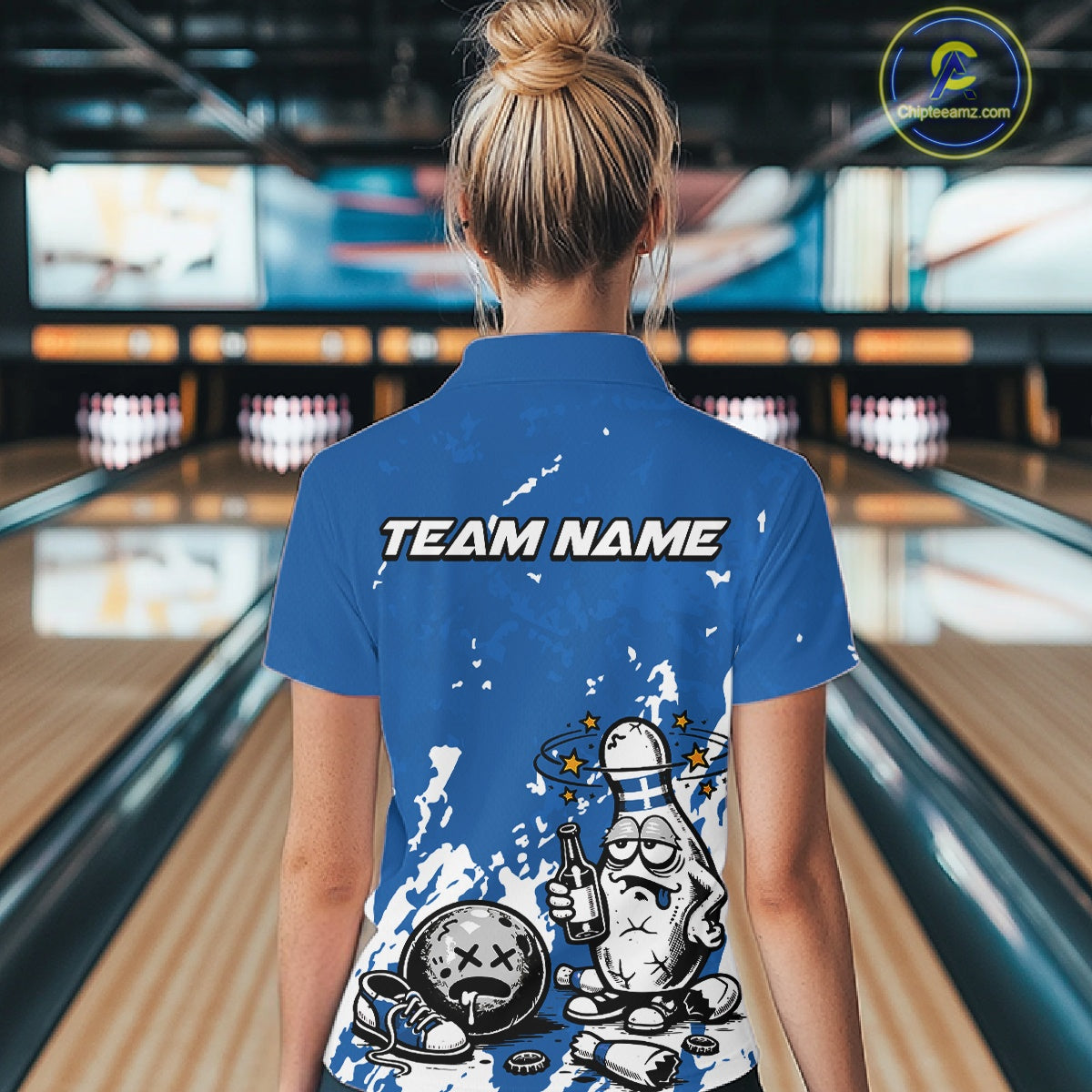 Back view female model wearing blue and white quarter zip bowling shirt in bowling lane, humorous bowling pin with beer bottle graphic