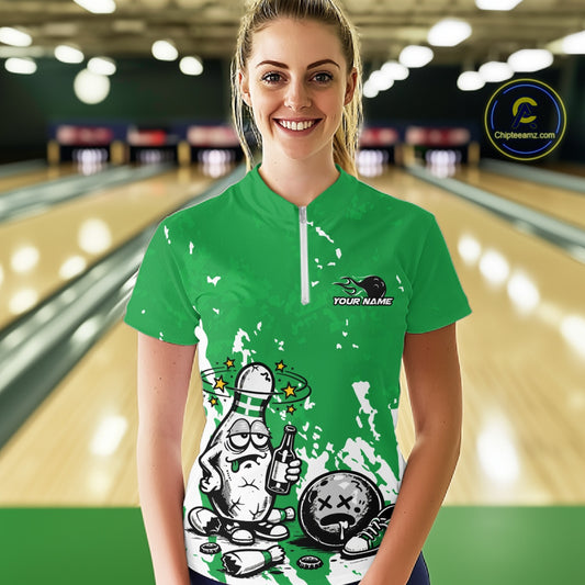 Front view female model in green and white quarter zip bowling shirt in bowling lane, playful beer drinking bowling pin graphic with splatter effect