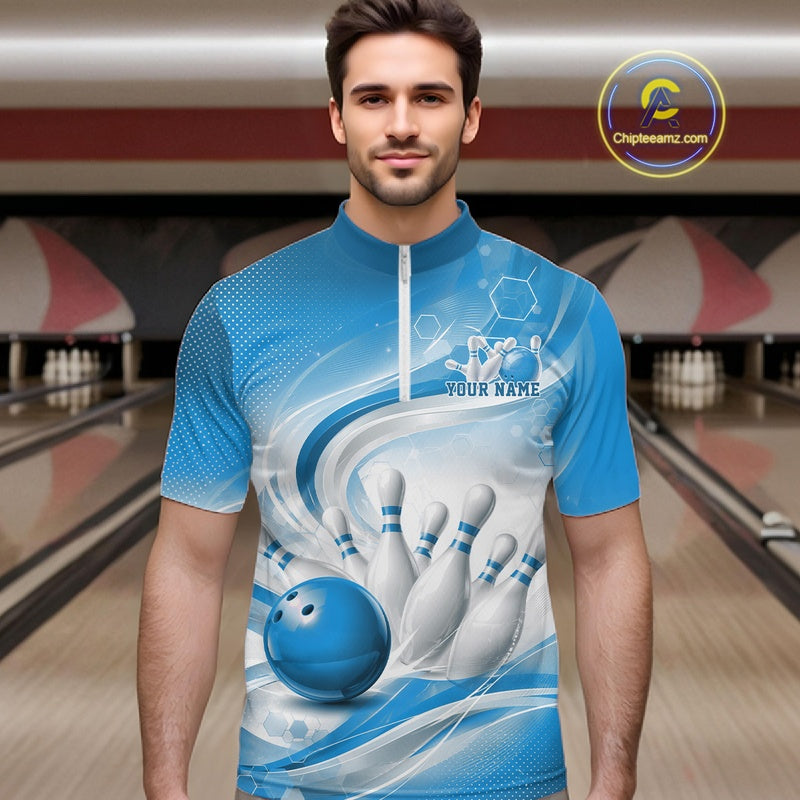 Male model standing in a bowling lane wearing a white and blue bowling quarter-zip shirt featuring abstract wave lines and a glossy bowling ball striking pins on the front.