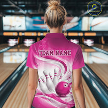 Load image into Gallery viewer, Back view of a female model wearing a white and pink bowling polo shirt in a bowling alley featuring flowing abstract wave patterns and a glossy bowling ball striking a set of pins