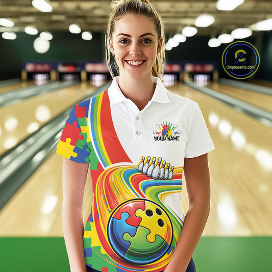 Female model in a bowling lane wearing a white polo shirt, front view featuring colorful autism-themed bowling lane artwork with puzzle-inspired graphics