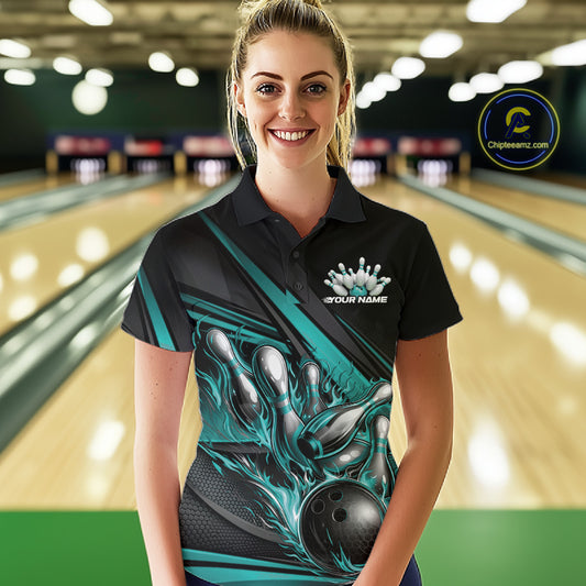 Female model in a bowling alley wearing black polo shirt, front view featuring turquoise flame bowling ball hitting pins geometric design