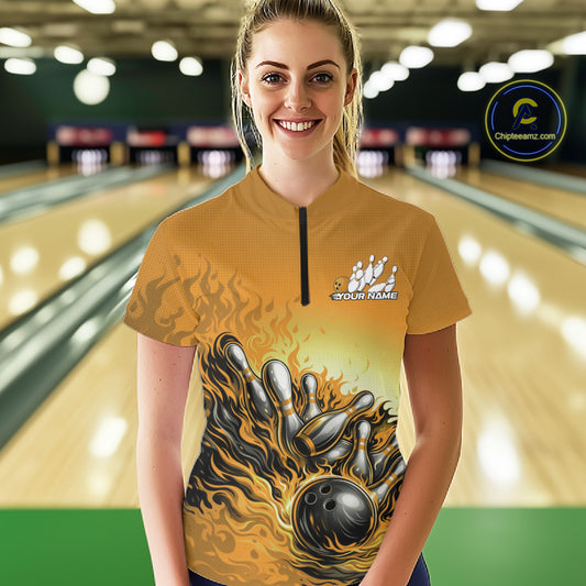 Female model in a bowling lane wearing a yellow quarter-zip shirt, flame bowling ball and pins artwork with energetic strike-themed graphics.
