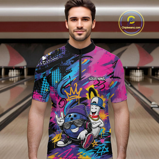 A man wearing a short-sleeve quarter-zip bowling jersey with a vibrant graffiti-style graphic print featuring cartoon bowling characters, set against a blurred bowling alley background.