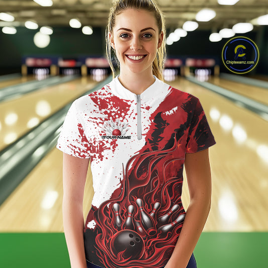 Front view of a female model in a bowling lane wearing a black quarter-zip shirt with red and white flame bowling ball and pins artwork and dynamic bowling visuals.