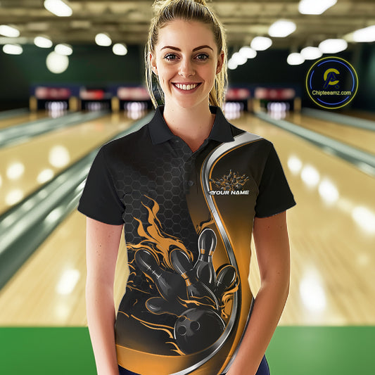 Female model front view in a bowling lane wearing a black and yellow polo shirt featuring flame bowling ball striking pins in a dynamic sports design.