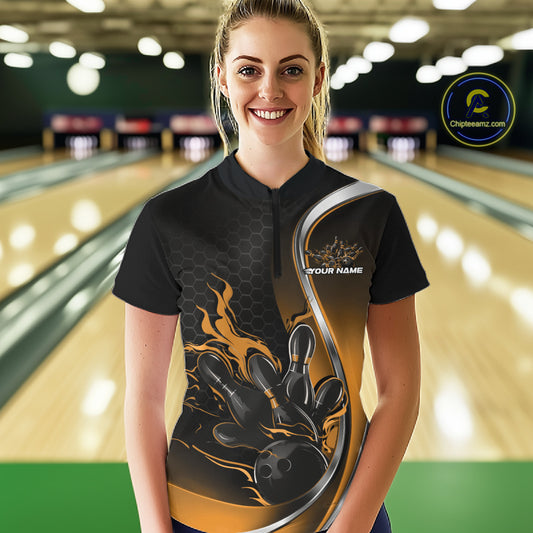 Female model front view at bowling lane wearing black and yellow quarter zip shirt with fiery bowling ball knocking down pins illustration
