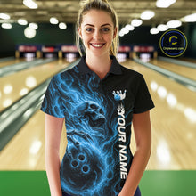 Load image into Gallery viewer, Female model wearing a black bowling polo shirt in a bowling alley featuring a skull clutching a bowling ball surrounded by swirling blue energy flames