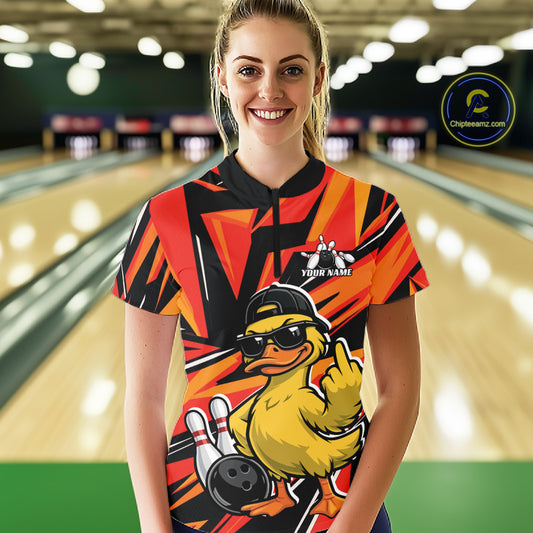 Front view of a female model at a bowling alley wearing a black and orange quarter-zip featuring a duck in sunglasses and cap.
