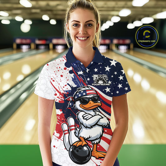Female model at the bowling lane wearing a bowling polo displaying a patriotic duck illustration with sunglasses and bowling-themed artwork.