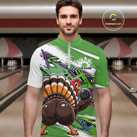 Front view of a male model wearing a green custom quarter zip bowling shirt with a funny graffiti turkey holding a bowling ball, paint splatter accents in a bowling alley.