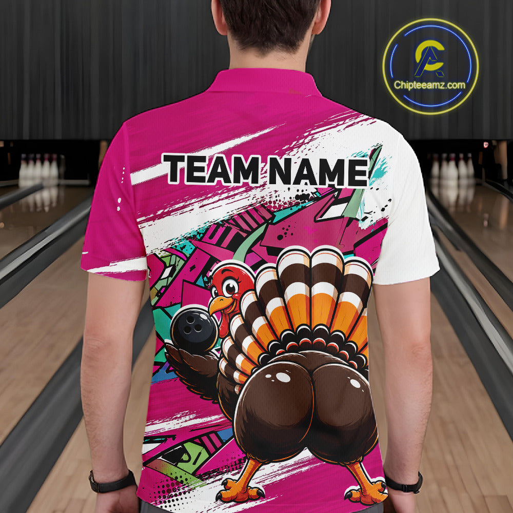 Back view of a male model wearing a pink custom bowling polo shirt with a funny graffiti turkey holding a bowling ball, paint splatter accents, and a personalized name in a bowling alley.