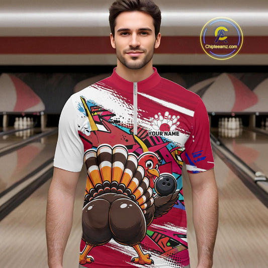 Front view of a male model wearing a red custom quarter zip bowling shirt with a funny graffiti turkey holding a bowling ball, paint splatter accents in a bowling alley.