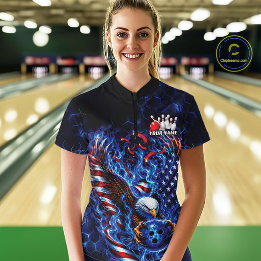 Front view female model at the bowling lane wearing a quarter zip shirt with flaming bald eagle graphics, blue bowling ball, American flag, and blue flames.