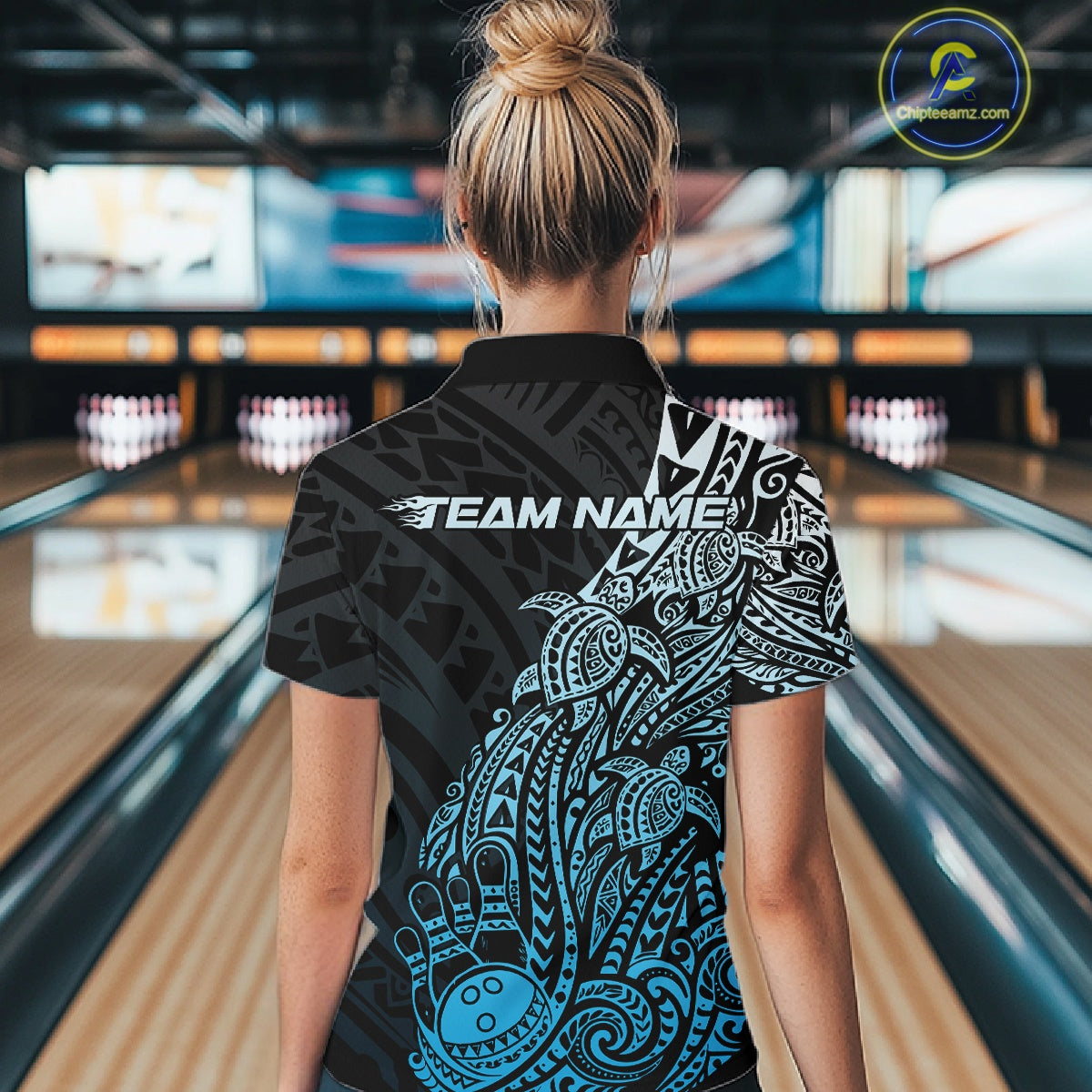 Back view of a female model in a black and blue bowling quarter-zip shirt displaying Polynesian bowling artwork and swirls.